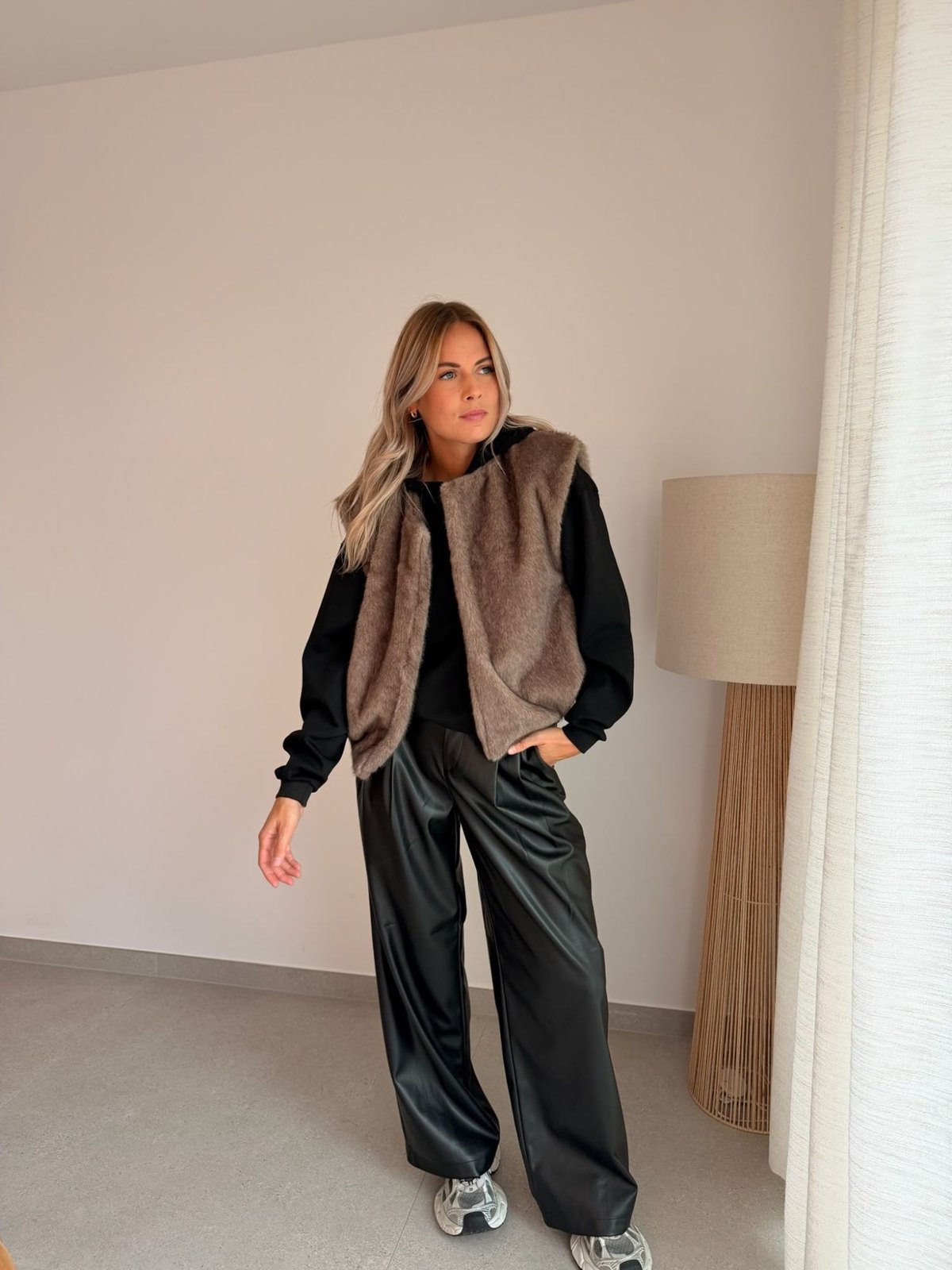 Gilet sans manches en fausse fourrure, sweat noir et pantalon simili cuir noir
